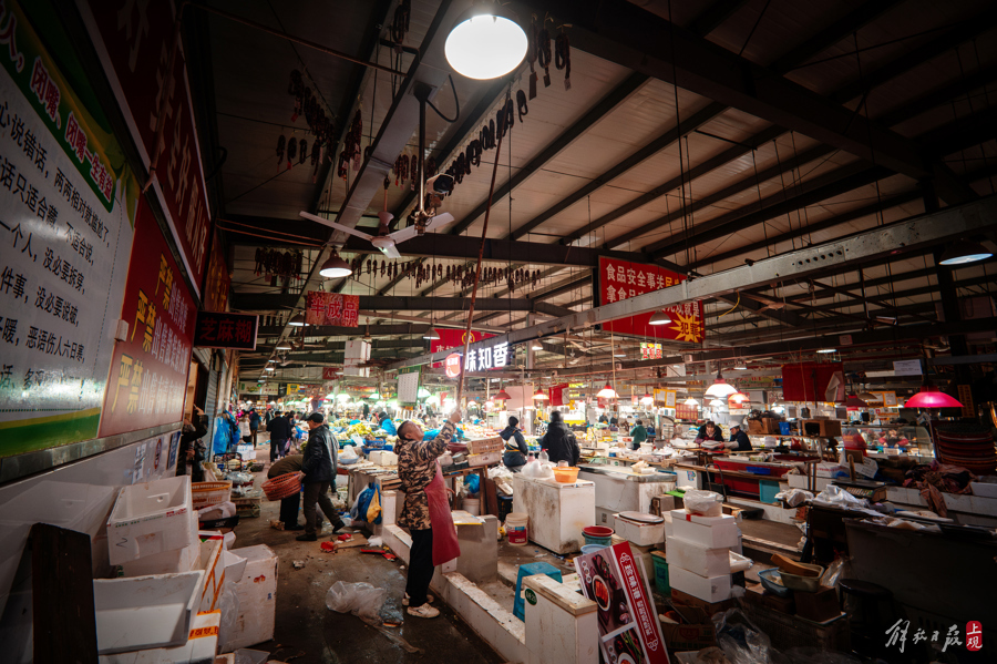 图为一位做腊肉的师傅将悬挂钢梁结构顶棚的腊肉取下来。记者 董天晔 摄  .jpeg