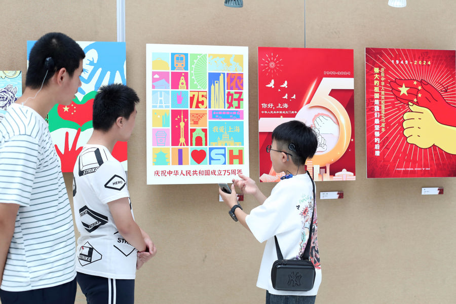 10岁的王梓骏(右)站在自己的画作前,一边翻着手机,一边用手语向他的朋友介绍其获奖作品《魅力上海》的创作过程。记者 蒋迪雯 摄 .jpg 10岁的王梓骏(右)站在自己的画作前,一边翻着手机,一边用手语向他的朋友介绍其获奖作品《魅力上海》的创作过程。记者 蒋迪雯 摄 .jpg