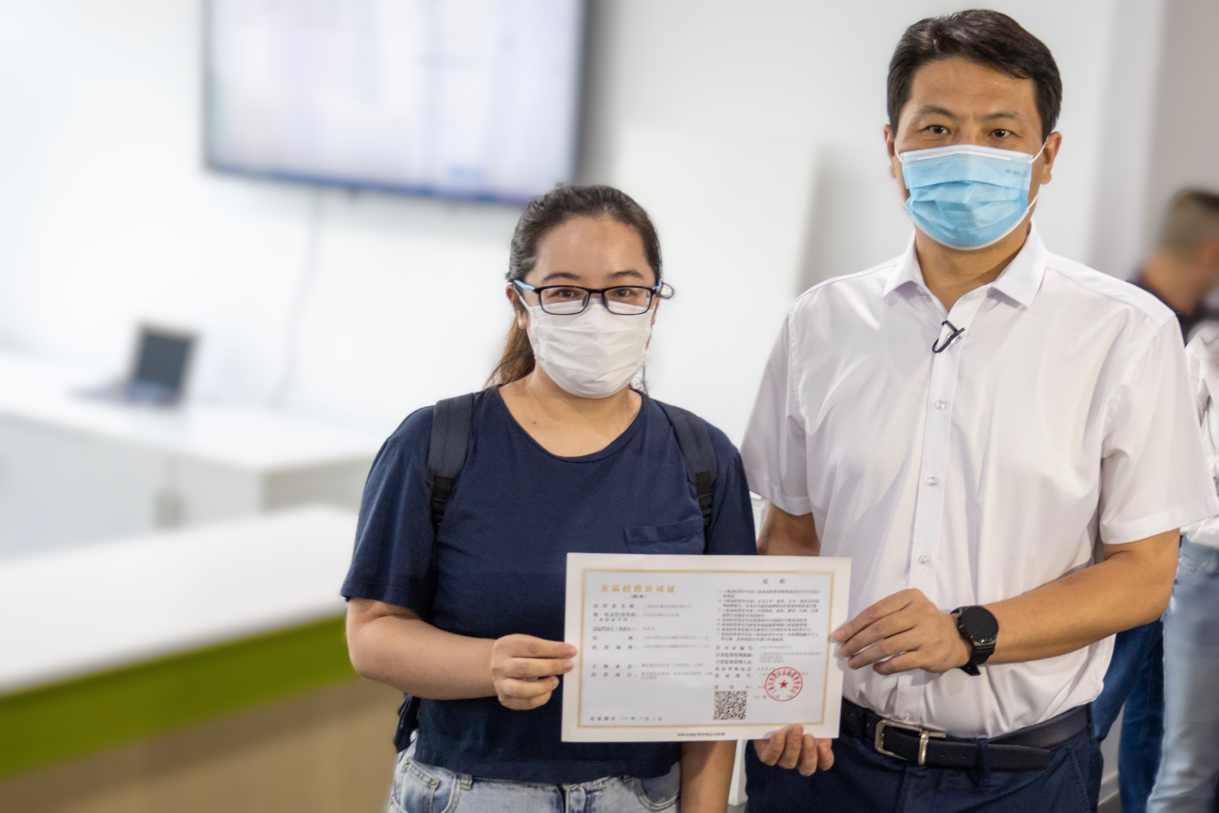 在“帮办”窗口，普陀区区长姜冬冬陪同餐饮企业经办人员办理食品经营许可证法定代表人变更业务