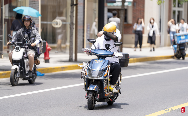 昨天，在茂名北路上，坚守配送岗位的外卖小哥用袖子擦去汗水.jpeg