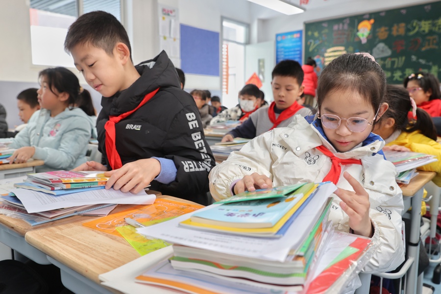 昨天，复旦大学附属徐汇实验学校的孩子们重返校园，领取新书。图为孩子们在清点刚刚发放的新学期课本。.jpeg