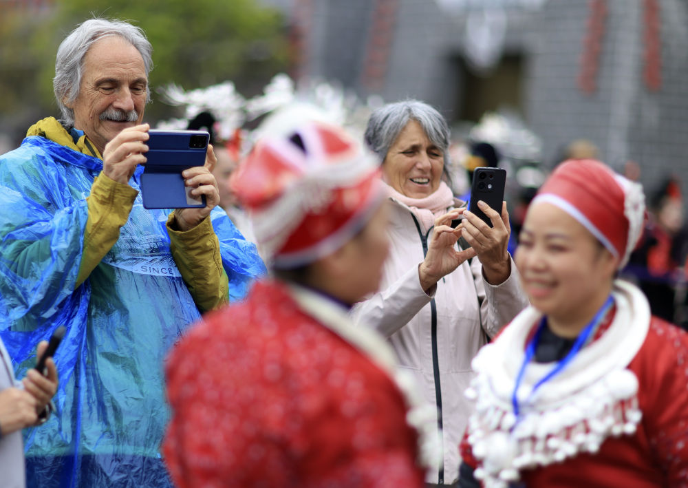 4月12日，外国游客在贵州省黔东南苗族侗族自治州台江县举行的“苗族姊妹节”庆祝活动上拍摄。新华社记者刘续 摄.jpeg