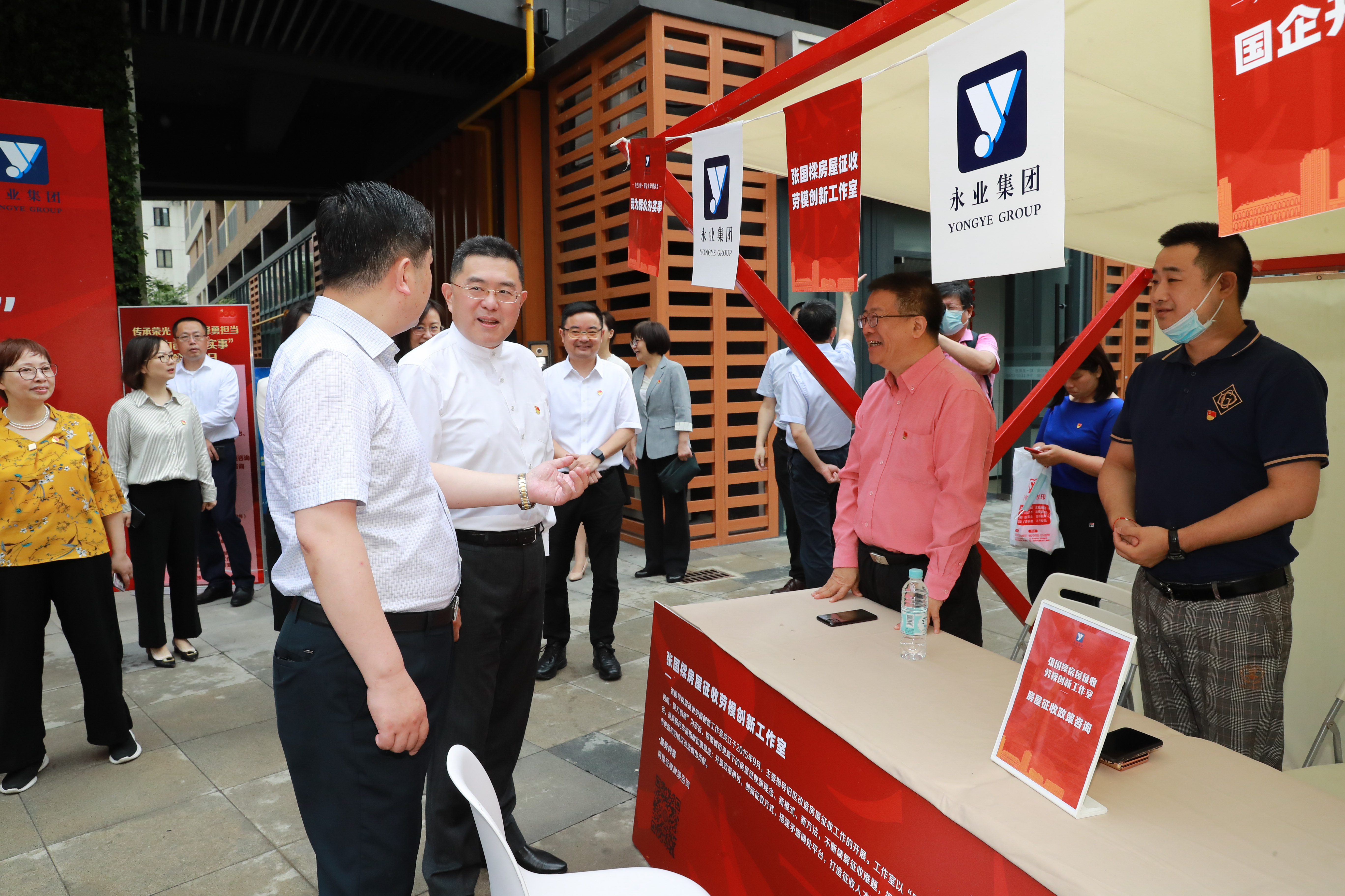 黄浦区副区长陈卓夫参加区国企开放日启动仪式，在张国樑房屋征收劳模创新工作室宣传摊位前了解情况